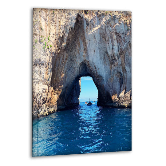 Geometric elements form an archway in this coastal rock formation, creating stunning art from glass with blue waters visible through the natural, framed landscape.