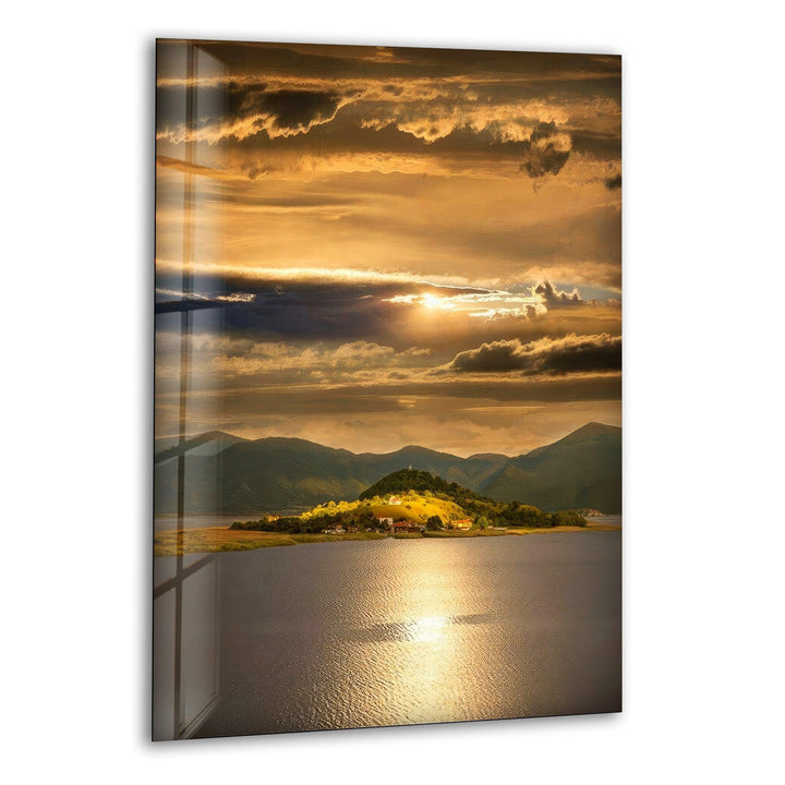 Glass wall art featuring a breathtaking golden sunset over a tranquil lake.
