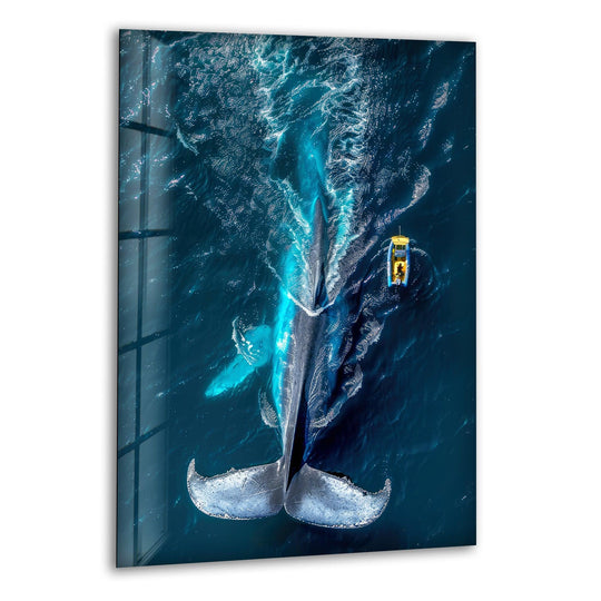 High-quality glass wall art decor captures a majestic blue whale surfacing in deep ocean waters with a tiny yellow boat nearby.