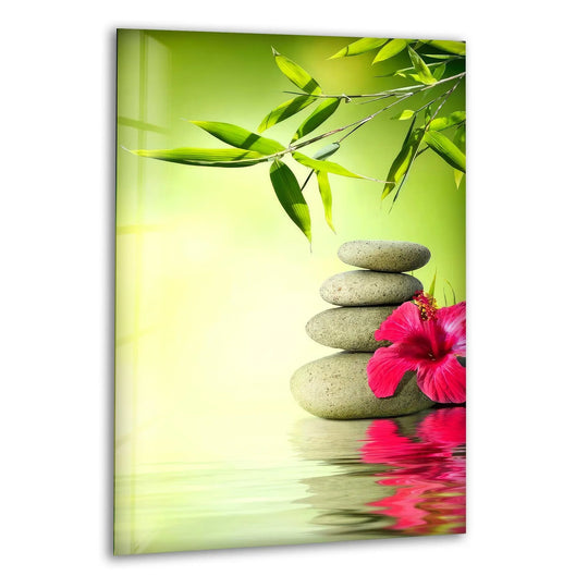 Vibrant pink hibiscus contrasts with soft green bamboo leaves and stacked spa stones on this glass art.
