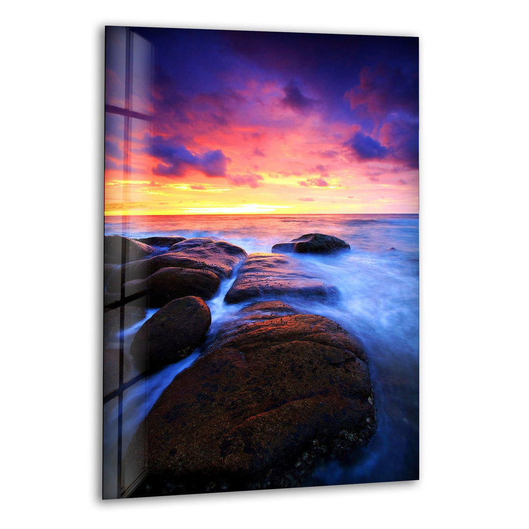 Breathtaking ocean sunset with waves flowing over coastal rocks, printed on glass wall art.
