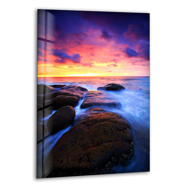 Breathtaking ocean sunset with waves flowing over coastal rocks, printed on glass wall art.
