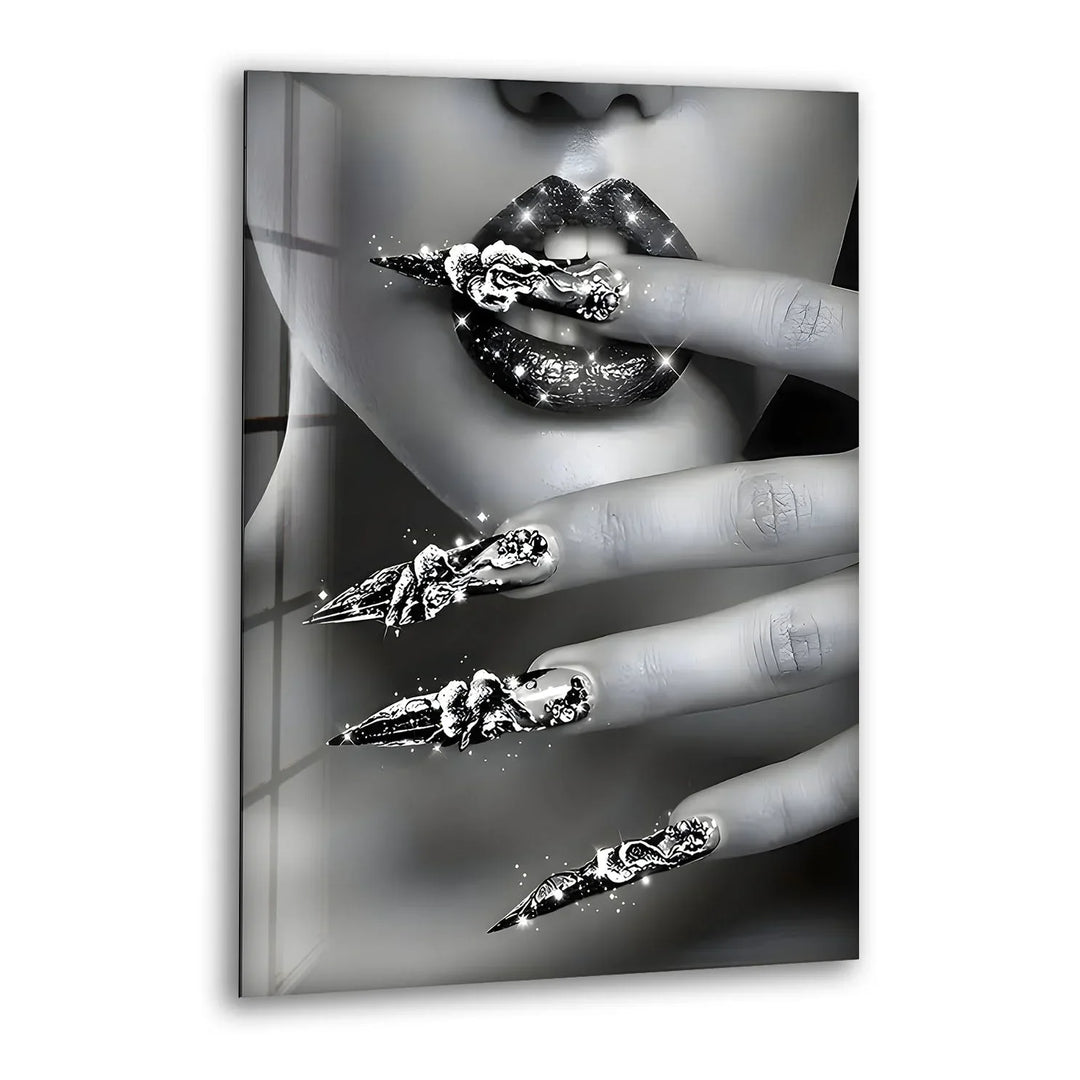 Black and white glass wall art featuring a close-up of glossy lips and dazzling metallic nail designs.