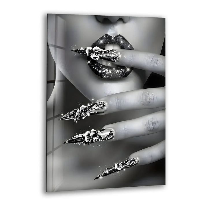 Black and white glass wall art featuring a close-up of glossy lips and dazzling metallic nail designs.