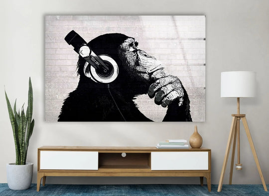 Banksy Dj Monkey Headphones glass wall art in black and white shows a monkey listening to music a piece of Banksy street art decor