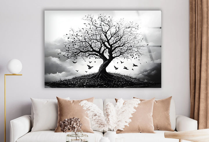 Dramatic black and white landscape on glass showing a bare tree on a hill surrounded by flying birds.