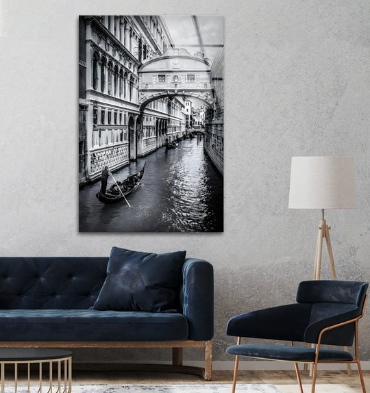 Repeating arched windows and the gondola's linear movement create a visual rhythm in this Venice Gondola Ride – Black & White Bridge of Sighs glass wall art decor.