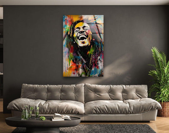 A vibrant glass wall art piece featuring a graffiti painting of Bob Marley, showcasing dynamic paint splashes and bold lines as home decoration.