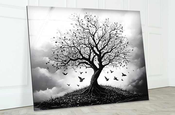 Atmospheric monochrome tree scene on glass with roots visible on a small hill and birds in motion.