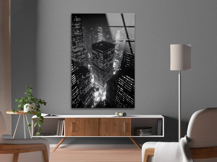 Black and white glass print of towering buildings lit up across a vibrant night city.