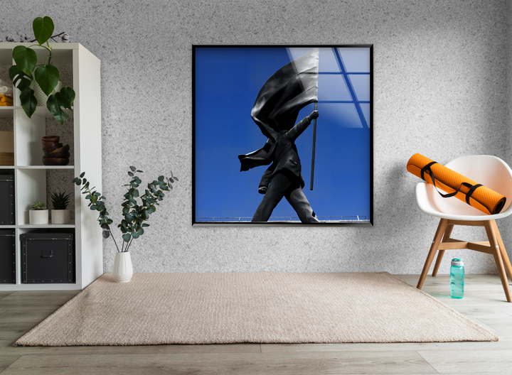 The striking Banksy Flag Statue tempered glass wall art featuring a bold perspective statue against a vibrant blue sky dominates this modern room.