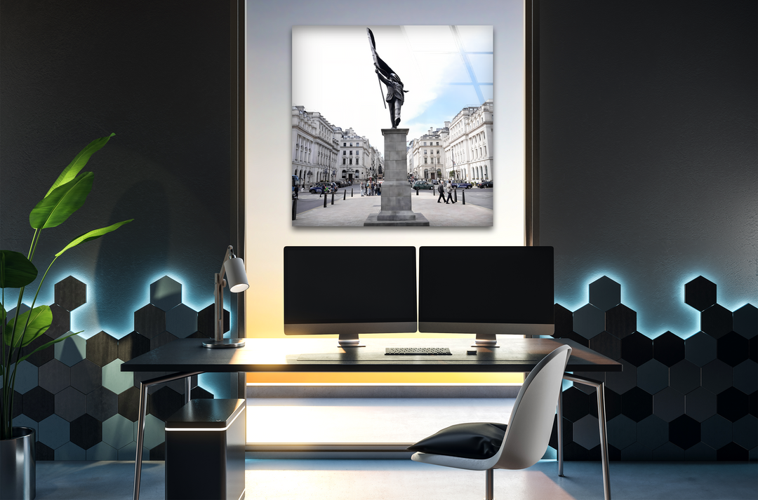 Layering effect beautifully frames the city square glass wall art decor, appearing over a bright window with a desk in the foreground.