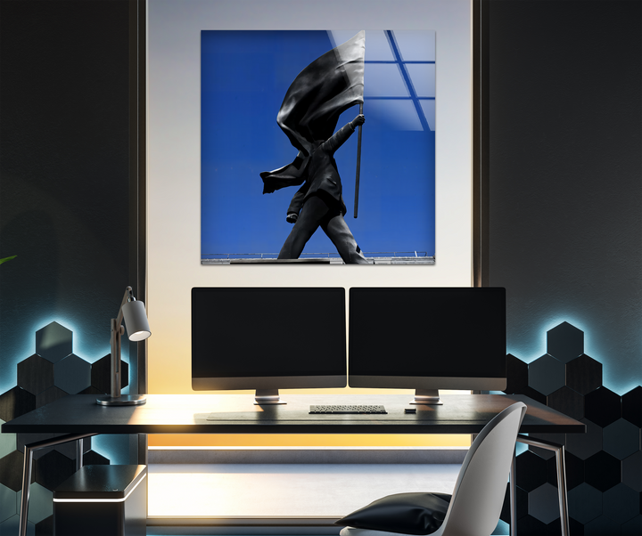 The abstract quality of this Banksy art from glass captures the dynamic form of a flag-bearing statue against a stark blue sky.
