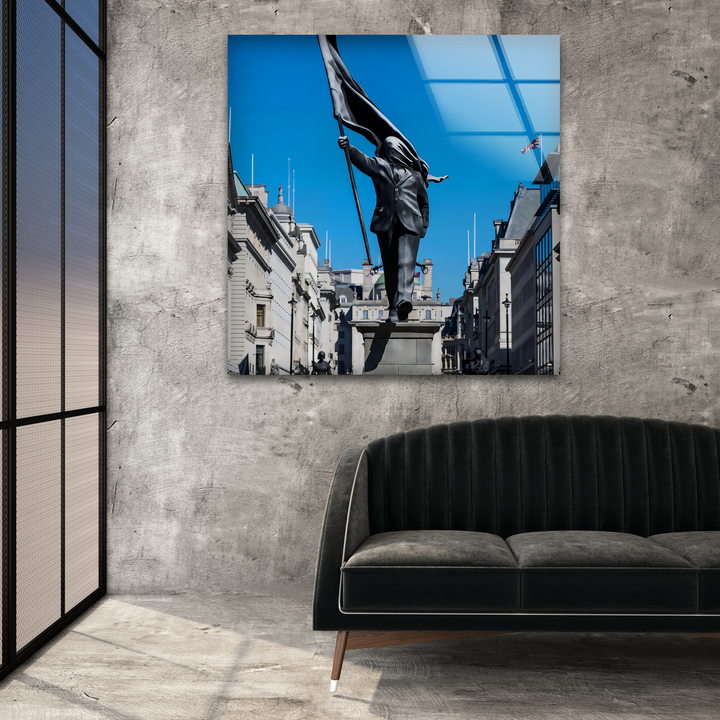 The reflective glass wall art creates a profound layering effect, featuring the dynamic Banksy statue under a blue sky as compelling home decor.