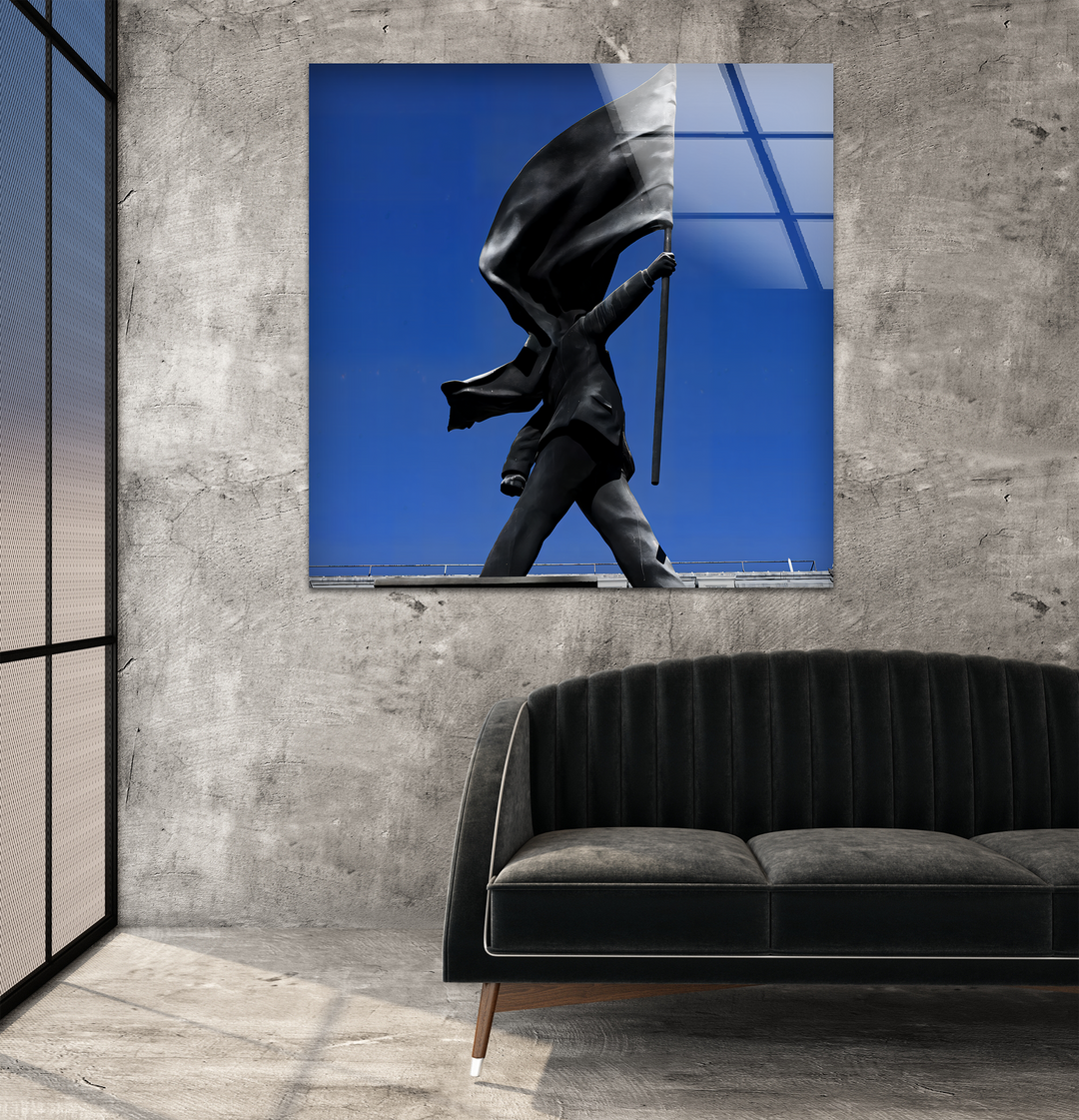 A dark, plush, channel-tufted sofa with slender wooden legs is prominent in the foreground, below the impactful Banksy art from glass.