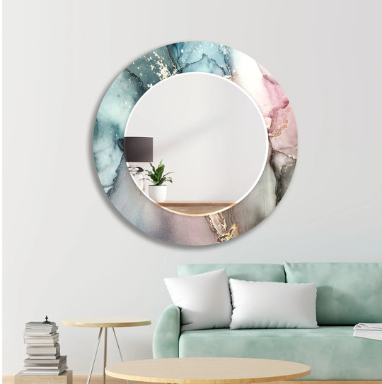Round wall mirror with an artistic abstract fluid design in vibrant blue pink and gold tempered glass on a light wall