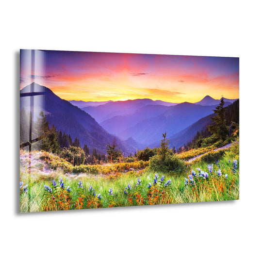 Landscape glass wall art mountain sunset meadow featuring wildflowers in green and orange and a breathtaking sunset landscape print for nature lovers