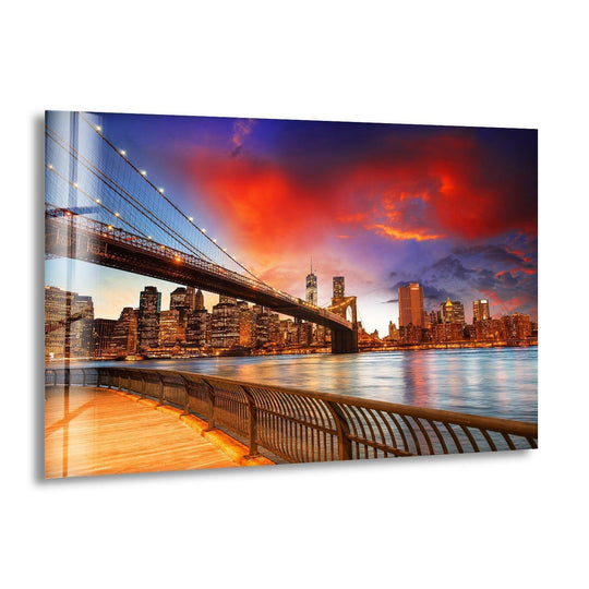 Brooklyn Bridge Park glass wall art showcases a vibrant city skyline and glowing lights and features a wooden boardwalk and dramatic sunset colors