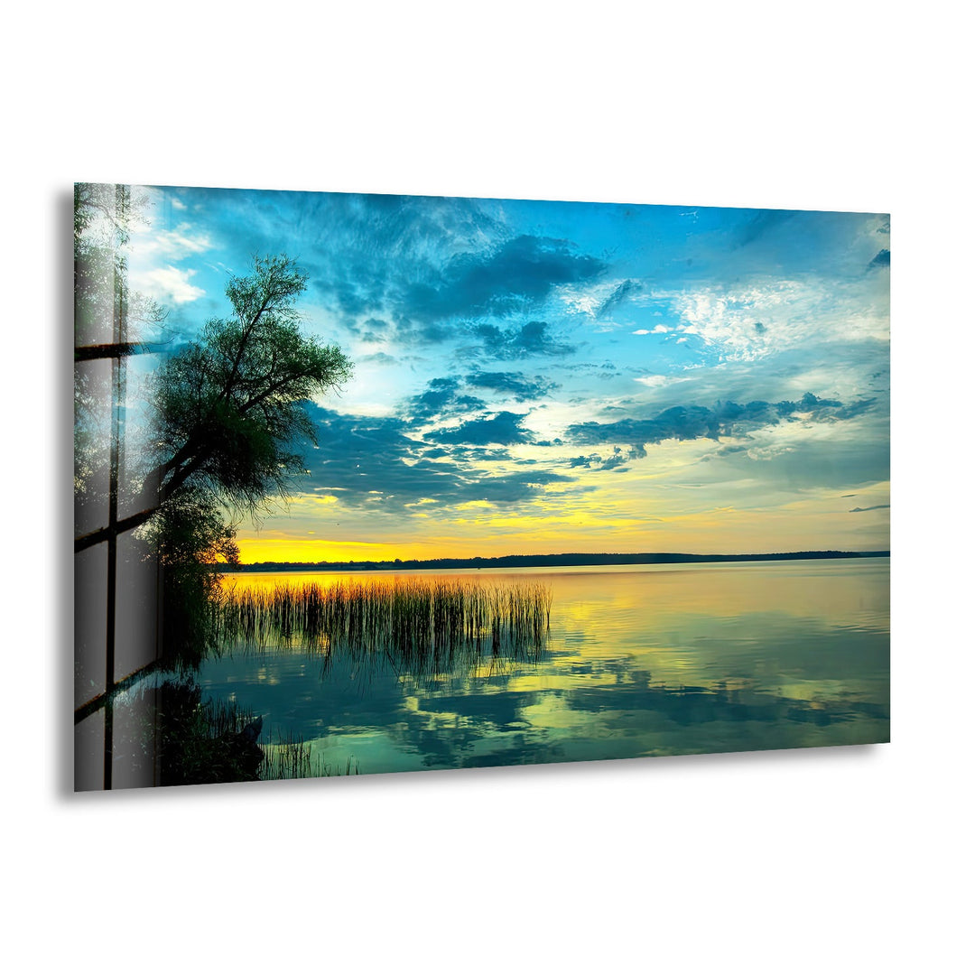 Golden sunset reflecting on a tranquil lake with lush trees, printed on glass wall art.
