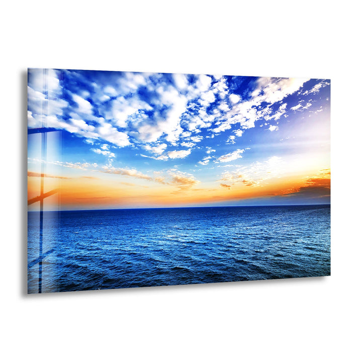 A breathtaking ocean horizon with a golden sunset and deep blue waters, printed on glass wall art.
