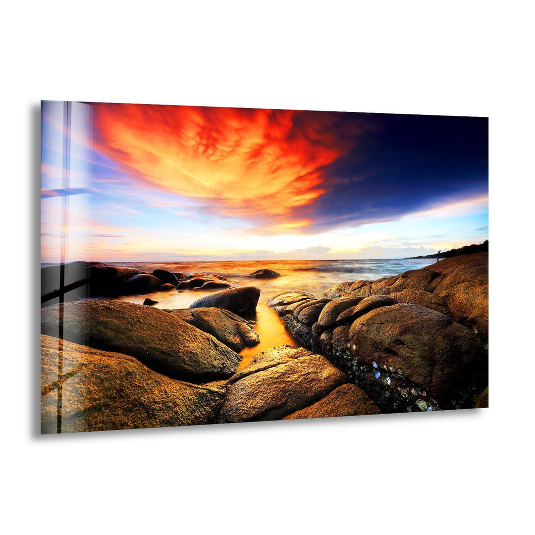 Golden sunset over rocky coastline with warm reflections on the ocean.
