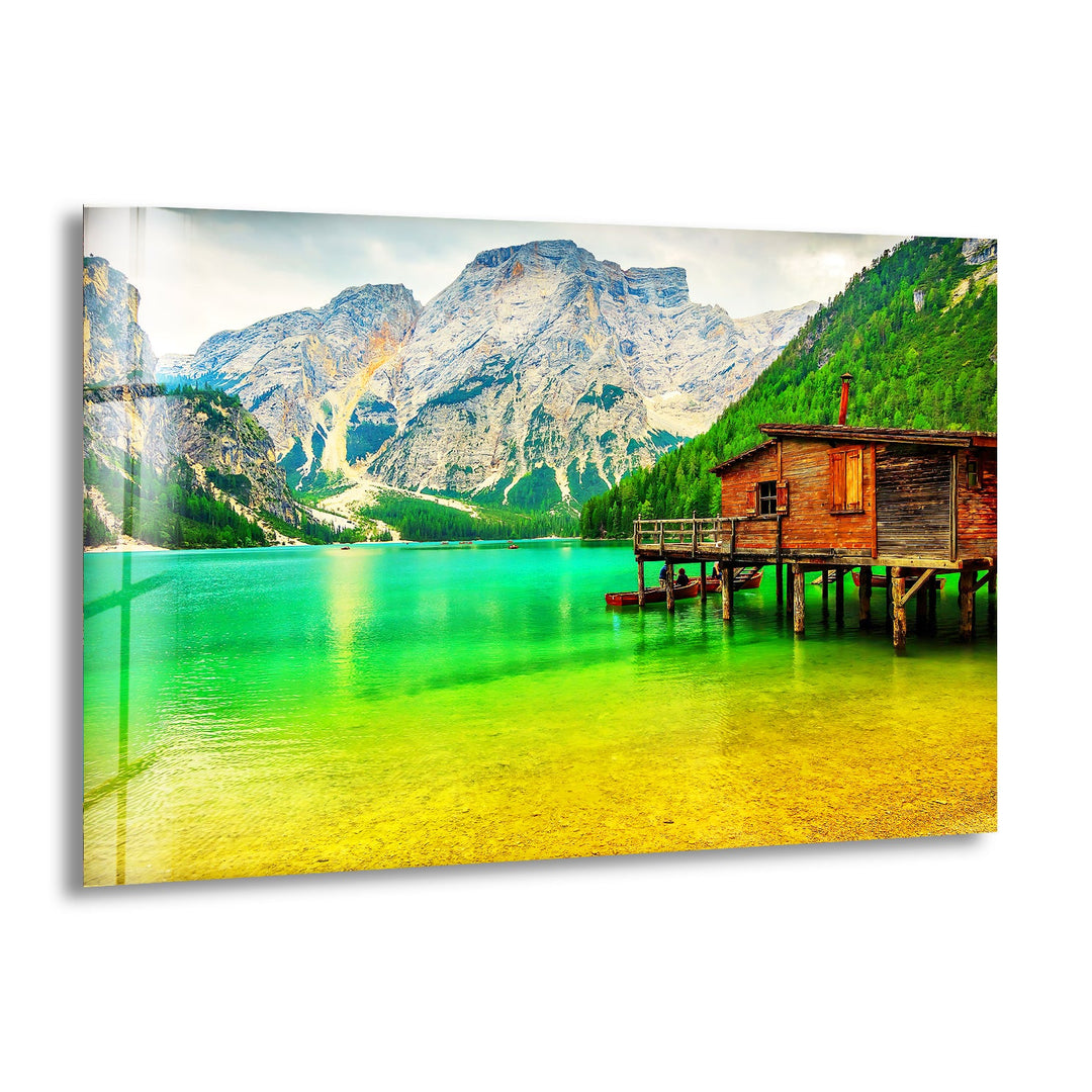 A breathtaking glass wall art featuring a tranquil mountain lake with a rustic wooden cabin.
