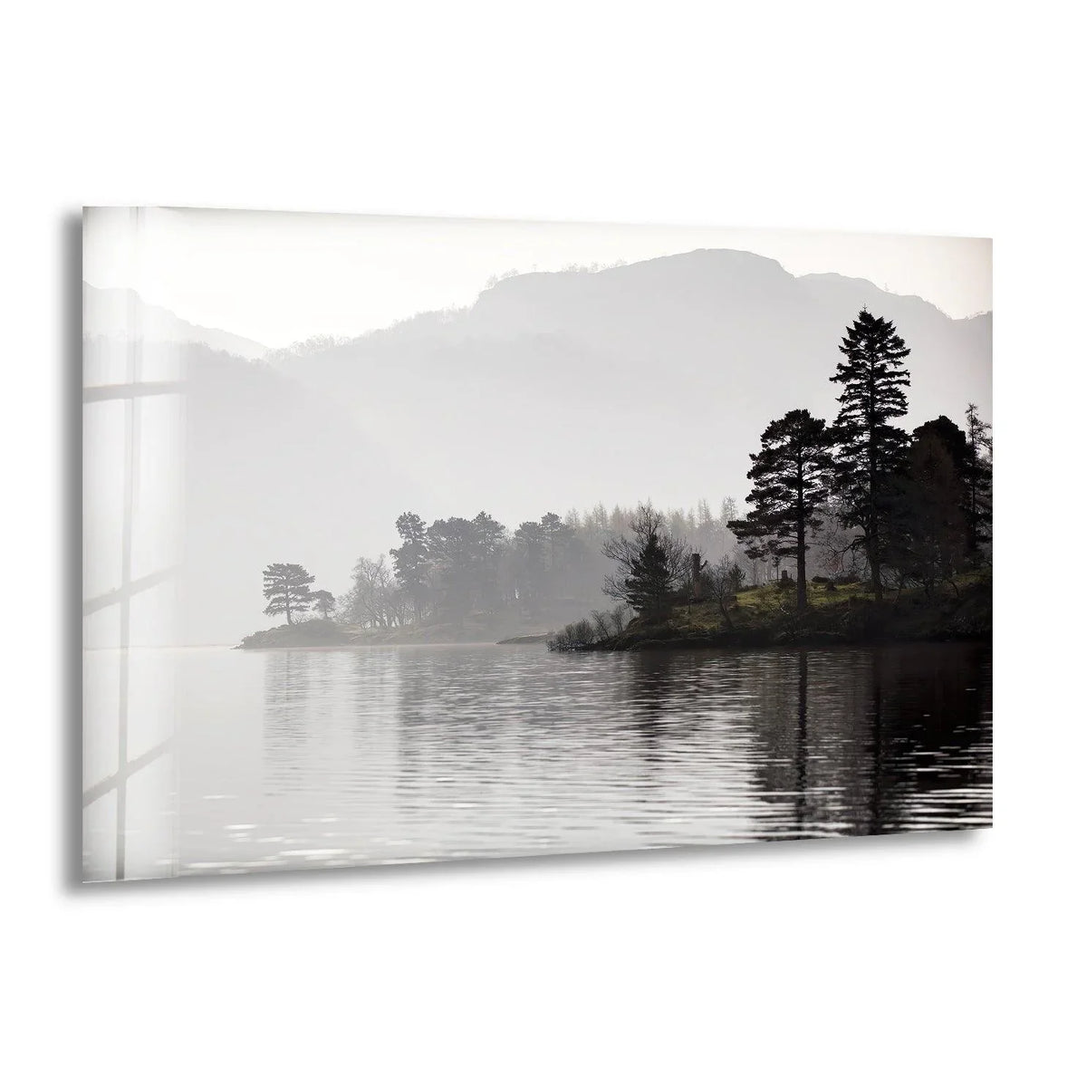 Silhouetted mountains fade into the misty background of this foggy trees and lake scene, printed on tempered glass wall art to highlight its serene beauty.