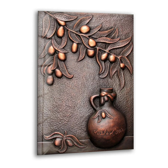 A bronze metal artwork features a branch of olives with geometric leaves above a rounded jug.