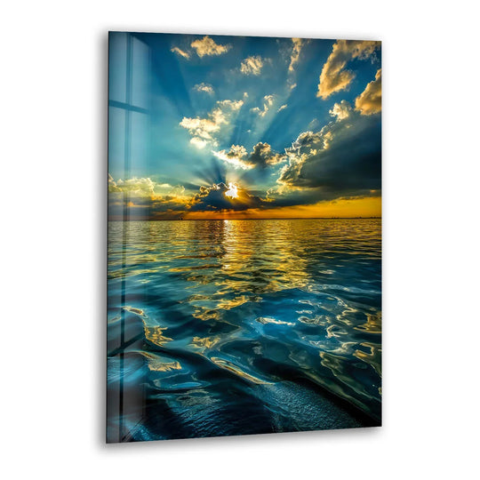 Glass wall art showcasing vibrant golden sunbeams piercing dark clouds above a shimmering cobalt sea.