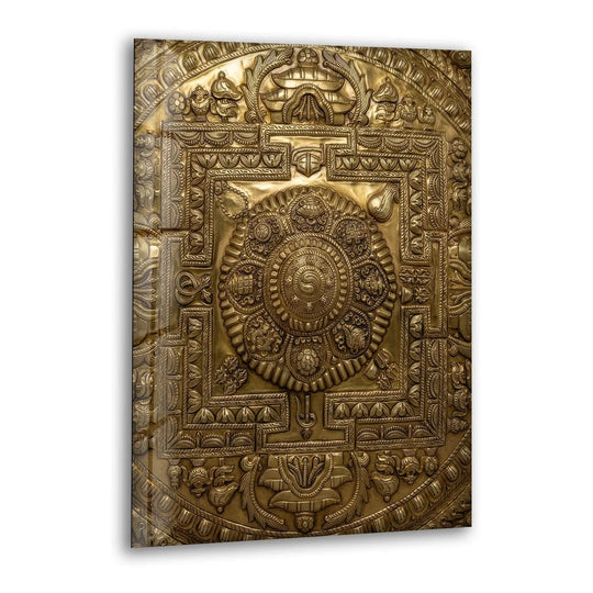 A gleaming golden metal wall art piece features an intricate mandala with a polished, reflective finish.