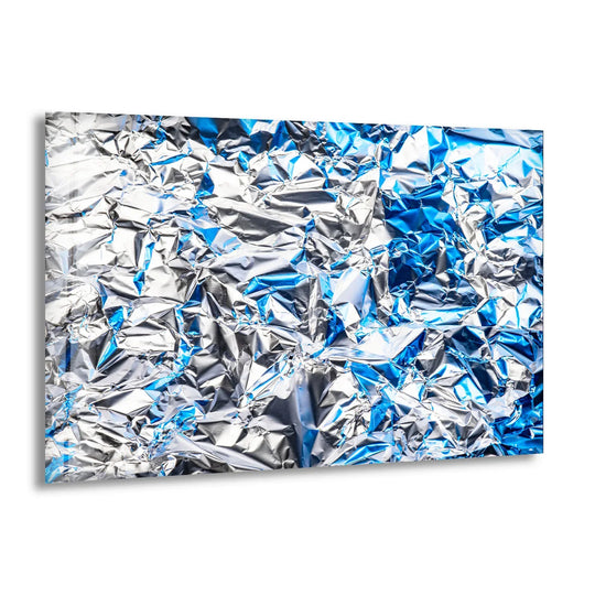 A horizontal abstract art from glass depicting crumpled silver and blue foil with sharp geometric shapes and folds.