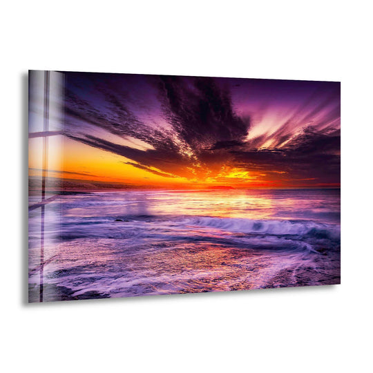 The focal point illuminates the vibrant ocean sunset wall art, showcasing the decorative wall art quality of the purple sky and crashing waves in this glass print.