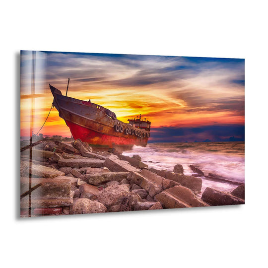 Dominant shades of orange and red paint a dramatic sunset seascape over an abandoned ship in this hanging wall art glass print.