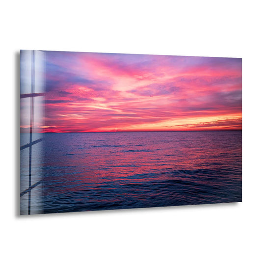 Vibrant color contrast highlights the tempered glass pink ocean sunset horizon wall art, making it a stunning piece of home decor for a serene seascape.