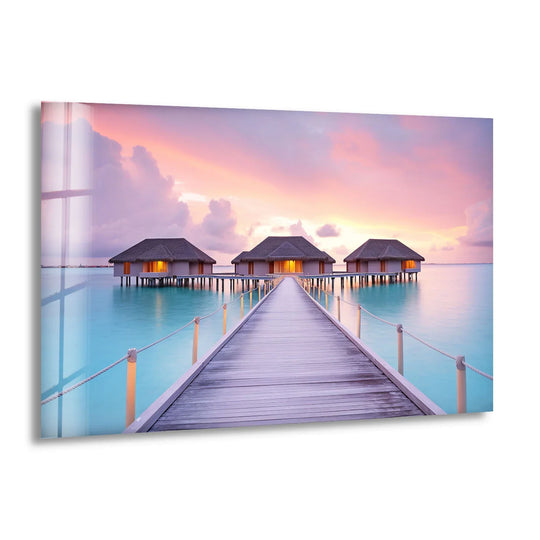 Horizontal shaped overwater bungalows wall art showcases a tropical sunset scene with glass printing that highlights the serene boardwalk leading to the island huts.