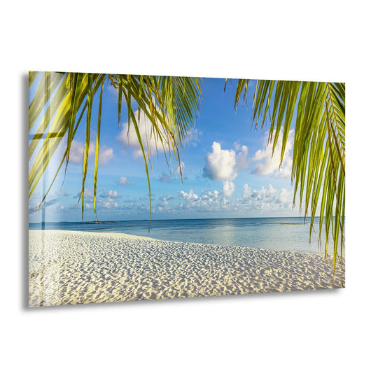 Rippling wind animates the palm fronds framing this tropical beach glass print wall art, suggesting the ocean's gentle sway over white sand.
