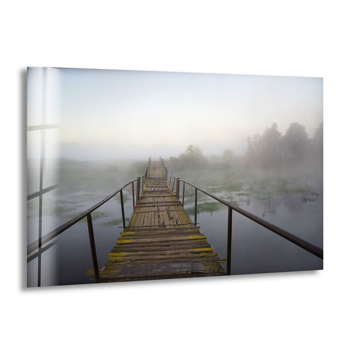 Serene wooden bridge disappearing into the morning mist over a reflective lake.
