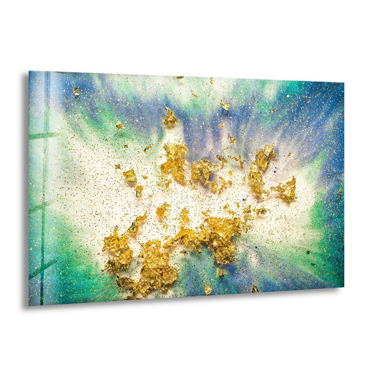 A horizontal abstract glass wall art piece features a dynamic splash of gold leaf and glitter on a blue and green epoxy background.