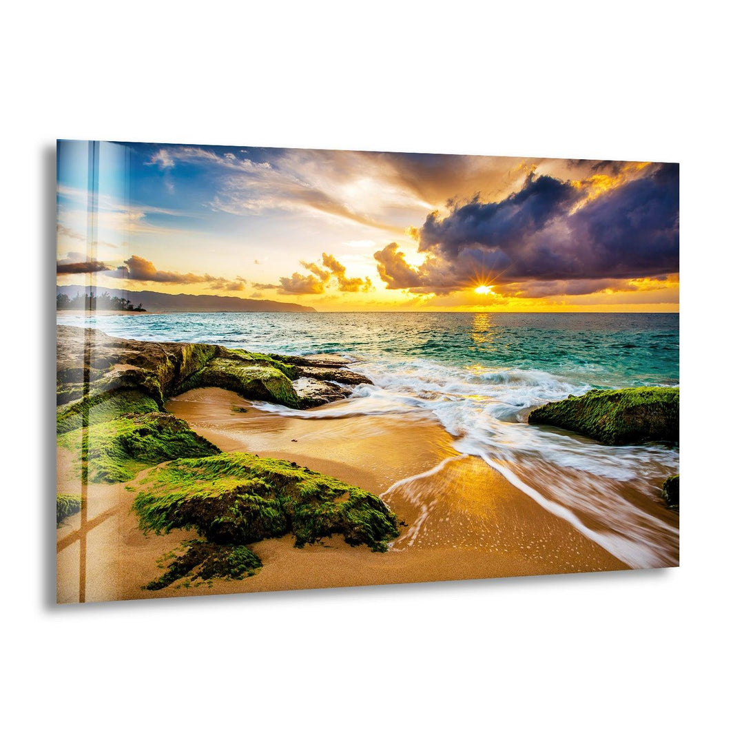 A breathtaking golden sunset on a rocky beach, with ocean waves washing over moss-covered stones.
