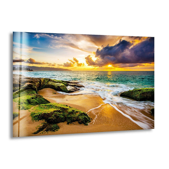 Landscape glass wall art shows a golden sunset over the ocean and rocky beach and this coastal view glass art offers stunning scenic beauty and a serene ambiance