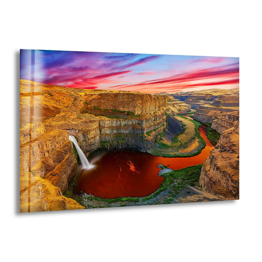 A breathtaking aerial view of a canyon waterfall with a winding red-hued river.
