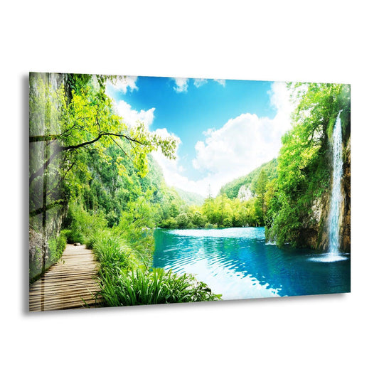 The horizontal glass wall art shows an emerald waterfall escape and serene nature landscape and is a high definition print for nature lovers and forest wall art