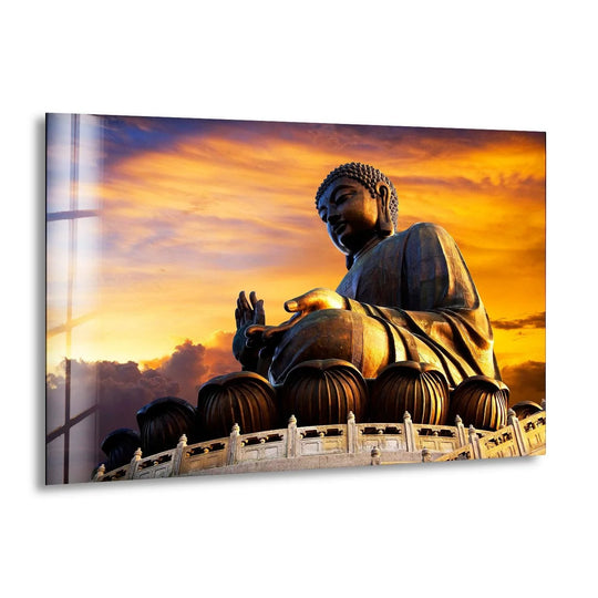 Glowing with golden and orange hues, the dramatic sunset in the background enhances the Tian Tin Buddha glass wall art as a vibrant piece of home decoration.