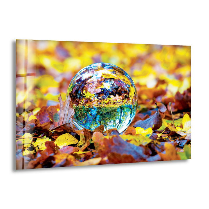 Glass wall art featuring a crystal sphere reflecting vibrant autumn leaves on the forest floor.
