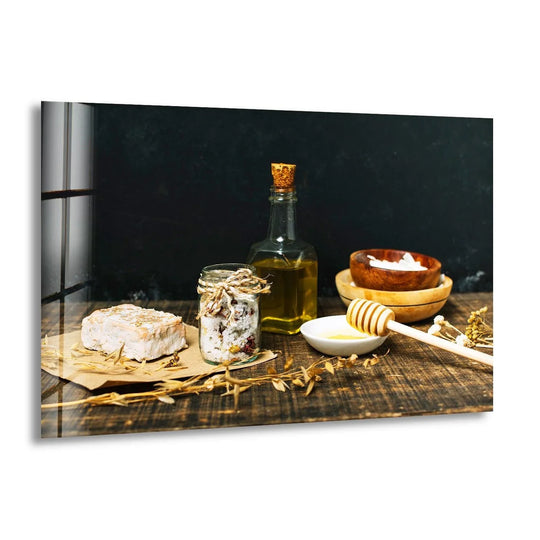 Horizontal glass wall art depicting a rustic kitchen still life with olive oil, honey, and cheese on a wooden table for modern wall decor.