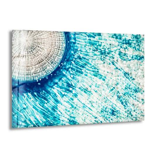 Striking contrast of bright turquoise blues against a pale, textured circular form in this glass wall art decor.