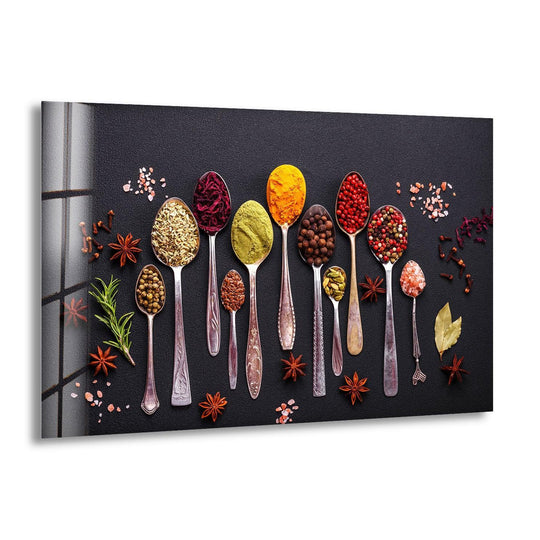 Horizontal glass wall art displaying colorful spices in vintage spoons against a dark background with star anise and bay leaves for kitchen decor.