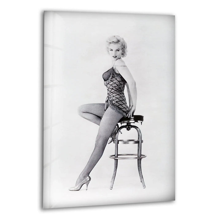 Elegant black and white glass wall art featuring Marilyn Monroe posing on a stool in vintage attire.