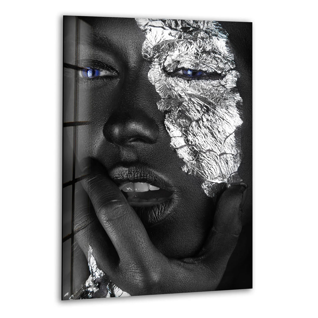 Striking black and white glass wall art featuring a metallic face design with vivid blue eyes.