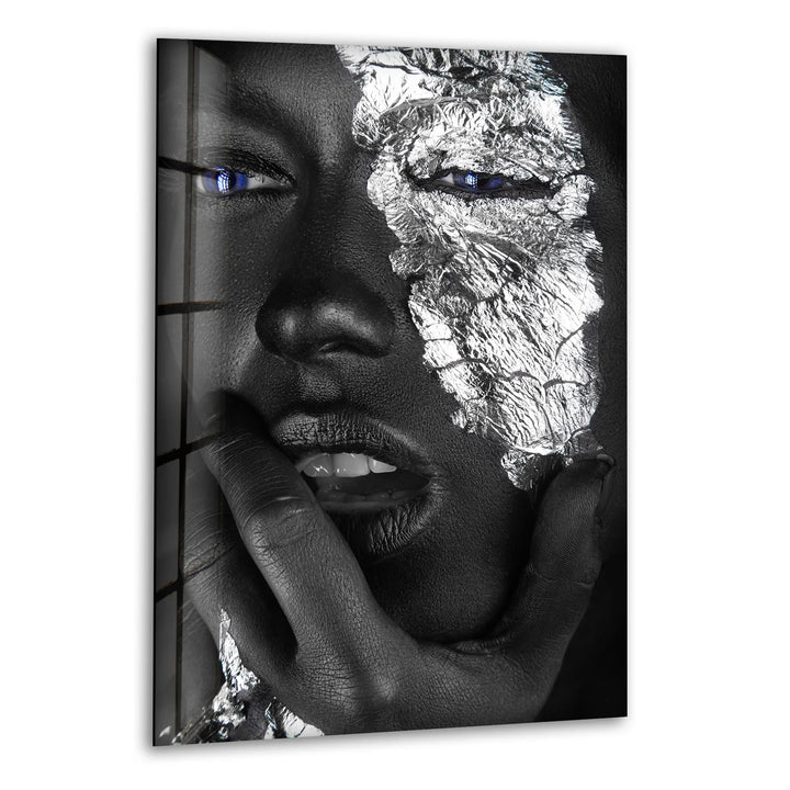 Striking black and white glass wall art featuring a metallic face design with vivid blue eyes.